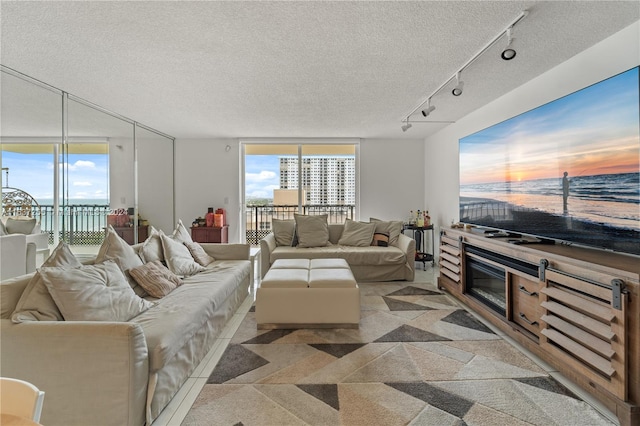 living room with a water view, a textured ceiling, expansive windows, and track lighting