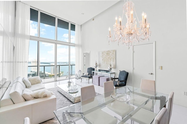 tiled living room featuring a water view, a chandelier, a wealth of natural light, and a high ceiling