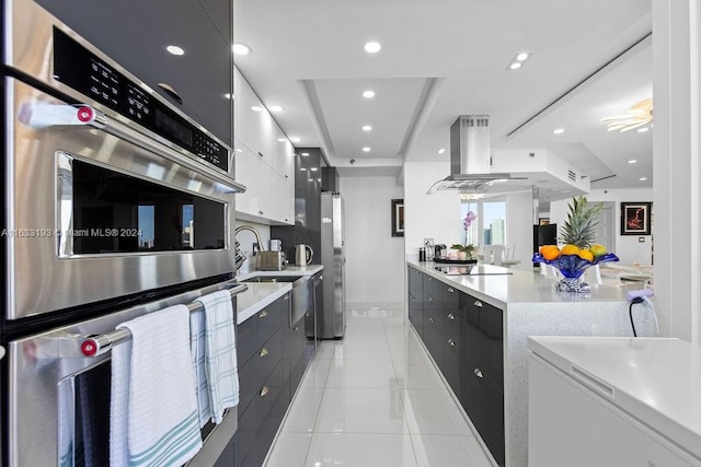 kitchen with white cabinetry, island exhaust hood, ceiling fan, appliances with stainless steel finishes, and light tile patterned flooring