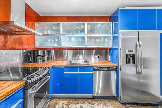 kitchen featuring sink, wood counters, wall chimney range hood, and stainless steel appliances