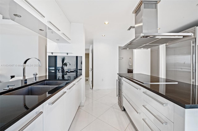 kitchen with white cabinetry, island range hood, light tile patterned floors, sink, and black electric stovetop