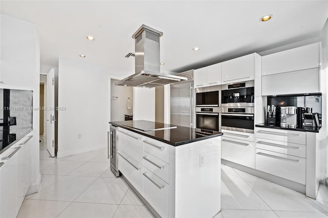 kitchen with light tile patterned floors, island exhaust hood, white cabinets, appliances with stainless steel finishes, and a kitchen island