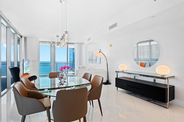 dining space with baseboards, a notable chandelier, a water view, and visible vents