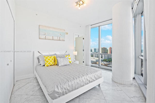 tiled bedroom featuring a wall of windows and a closet