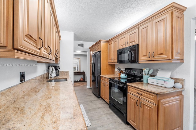 kitchen featuring sink, a textured ceiling, light hardwood / wood-style flooring, and black appliances