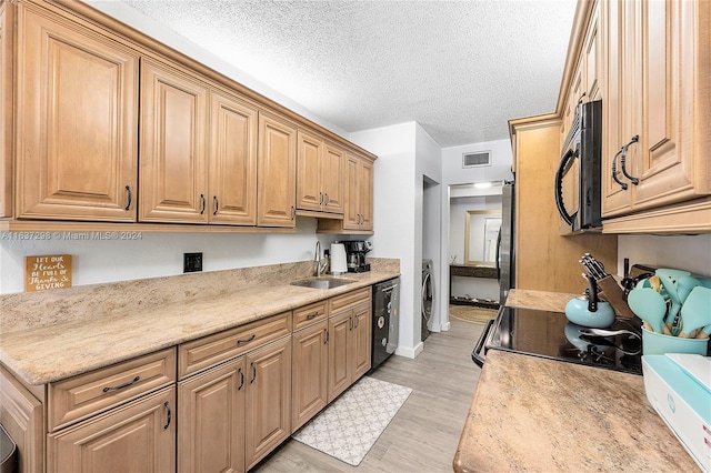 kitchen with sink, a textured ceiling, dishwashing machine, and light hardwood / wood-style floors