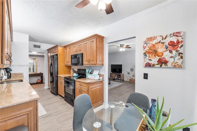 kitchen with black appliances, sink, light wood-type flooring, and ceiling fan