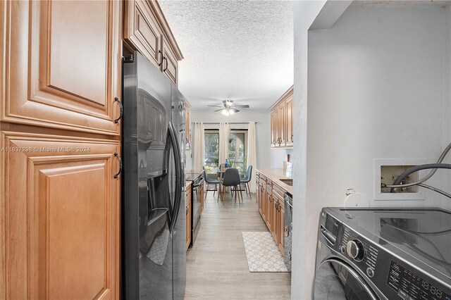 kitchen featuring ceiling fan, black refrigerator with ice dispenser, light hardwood / wood-style flooring, a textured ceiling, and washing machine and clothes dryer