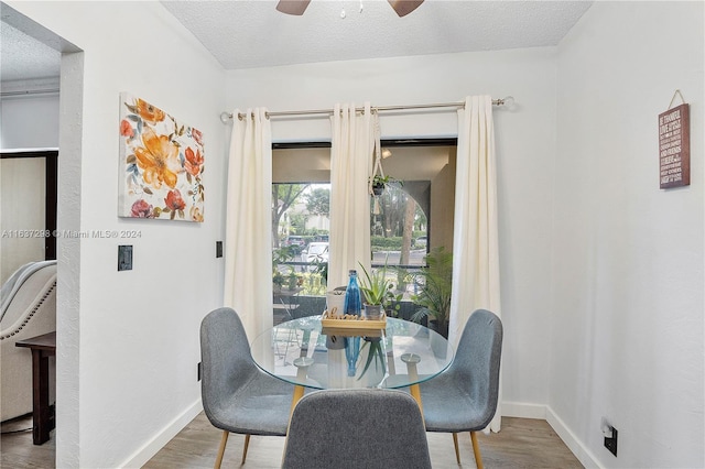 dining area with hardwood / wood-style flooring, ceiling fan, and a textured ceiling