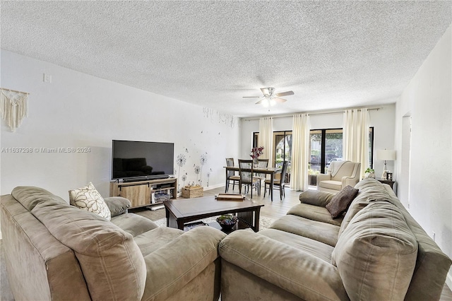 living room featuring ceiling fan, a textured ceiling, and light wood-type flooring