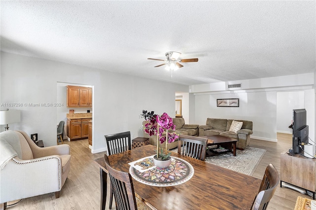 dining room featuring a textured ceiling, light wood-type flooring, and ceiling fan