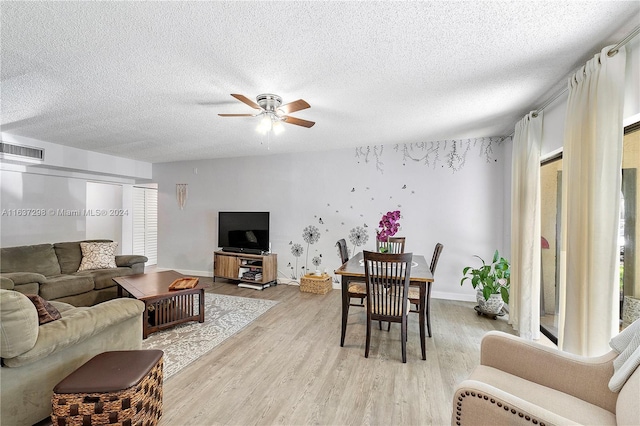 living room with light hardwood / wood-style flooring, a textured ceiling, and ceiling fan