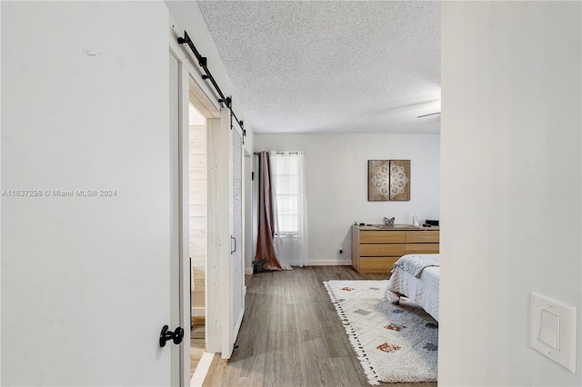 bedroom featuring hardwood / wood-style floors, a barn door, and a textured ceiling