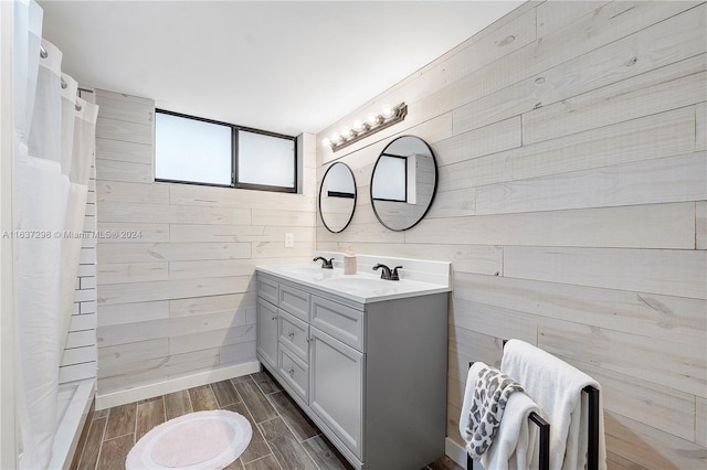 bathroom with wooden walls, a shower with shower curtain, and dual bowl vanity