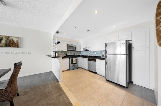 kitchen with appliances with stainless steel finishes, tasteful backsplash, white cabinetry, and a textured ceiling