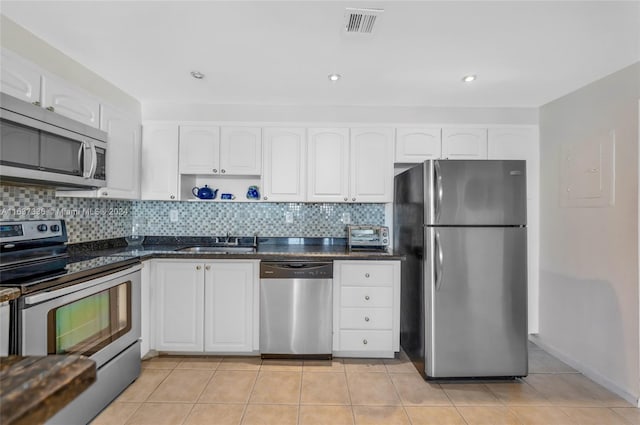 kitchen with sink, appliances with stainless steel finishes, white cabinetry, and light tile patterned flooring