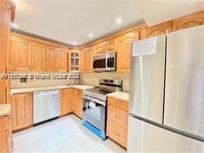 kitchen with range, light brown cabinets, dishwashing machine, light tile patterned flooring, and white fridge