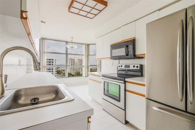 kitchen with white cabinetry, stainless steel refrigerator, light tile patterned floors, electric stove, and sink