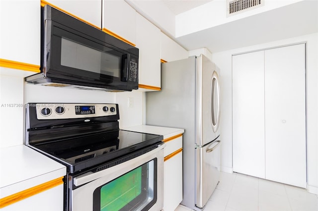 kitchen featuring light tile patterned flooring, white fridge, stainless steel electric range, and white cabinets