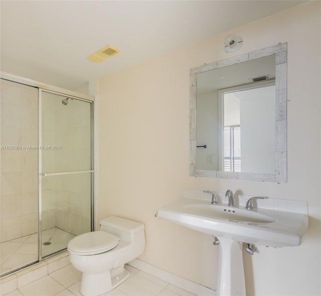 bathroom with tile patterned floors, toilet, and a shower with door