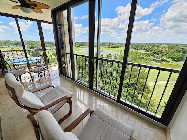 sunroom with ceiling fan and a water view