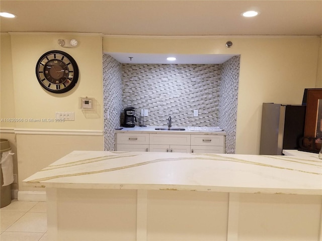 kitchen featuring light tile patterned floors, white cabinetry, tasteful backsplash, stainless steel refrigerator, and sink