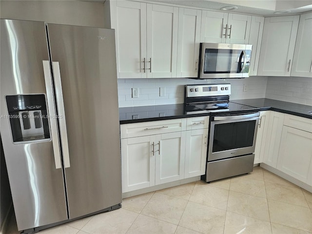 kitchen featuring light tile patterned floors, backsplash, appliances with stainless steel finishes, and white cabinetry