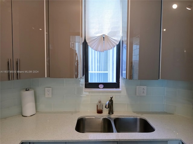 kitchen with sink, light stone counters, and backsplash