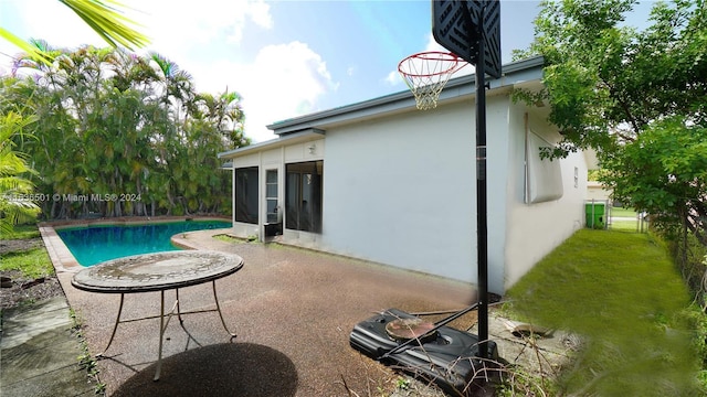 pool with a sunroom, a patio area, and a lawn