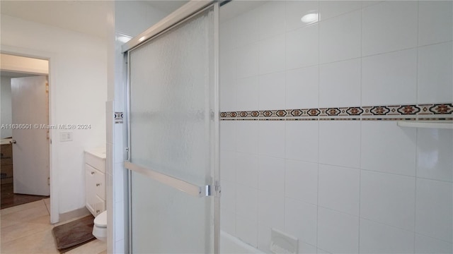 full bathroom featuring toilet, a shower with door, tile patterned flooring, and vanity