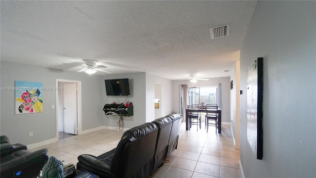 living room with ceiling fan, a textured ceiling, light tile patterned flooring, and visible vents