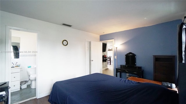 bedroom with ensuite bath, visible vents, and baseboards