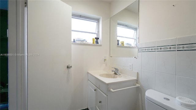 half bath featuring tile walls, toilet, and vanity