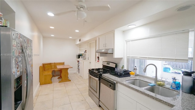 kitchen with light stone counters, stainless steel appliances, white cabinetry, a sink, and under cabinet range hood