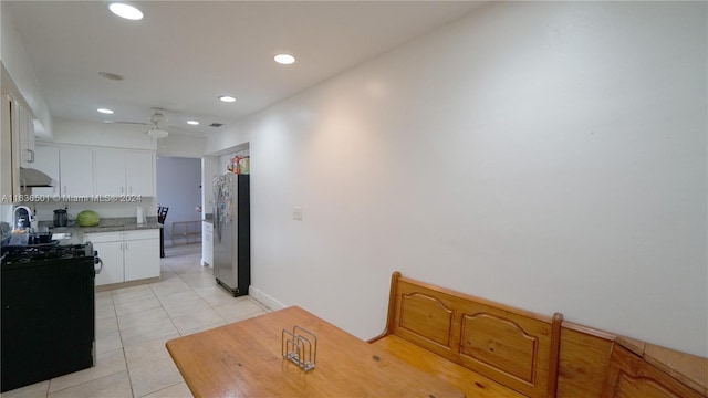 kitchen with light tile patterned floors, white cabinets, black stove, light countertops, and stainless steel fridge with ice dispenser