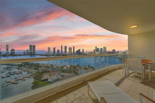 balcony at dusk with a view of city and a water view