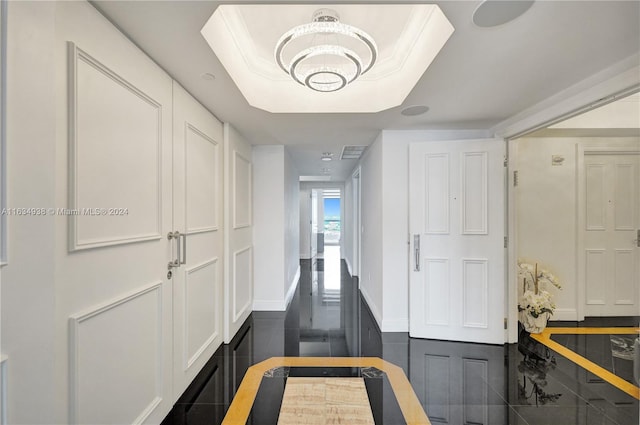 hallway featuring a raised ceiling and baseboards