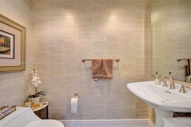 bathroom with sink, tile walls, and toilet