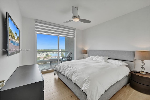 bedroom with ceiling fan, a water view, light wood-type flooring, and access to outside