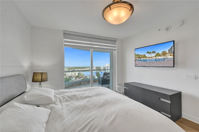 bedroom featuring access to exterior, wood finished floors, and baseboards