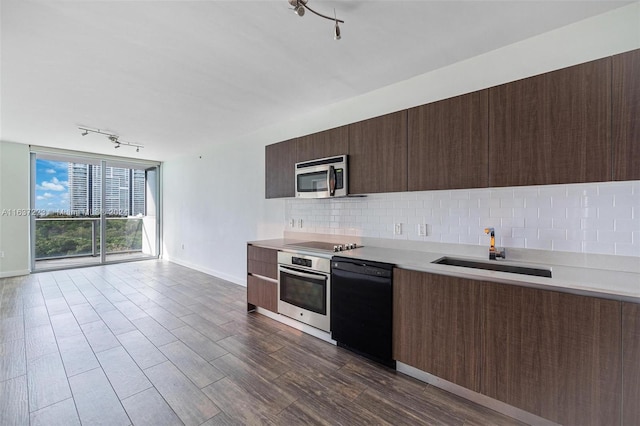 kitchen with dark wood-type flooring, tasteful backsplash, sink, rail lighting, and black appliances