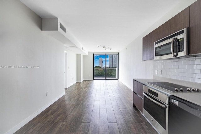 kitchen with appliances with stainless steel finishes, decorative backsplash, rail lighting, dark brown cabinets, and dark wood-type flooring