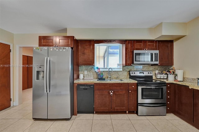 kitchen with stainless steel appliances, light stone counters, tasteful backsplash, and sink