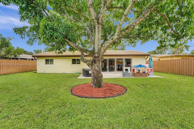 rear view of house featuring a lawn and a patio