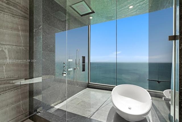 bathroom with tile walls, a shower with shower door, and a water view