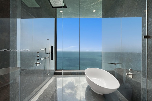 bathroom with tile walls, a water view, walk in shower, and tile patterned floors