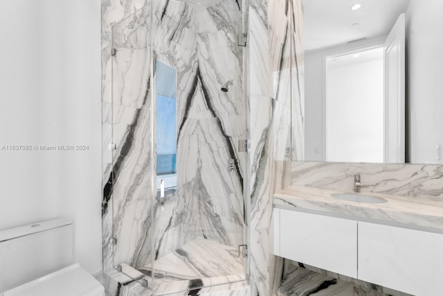 bathroom featuring a shower with shower door, toilet, and vanity