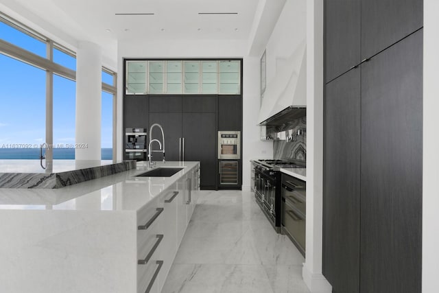 kitchen with range with two ovens, a water view, premium range hood, light tile patterned floors, and white cabinets