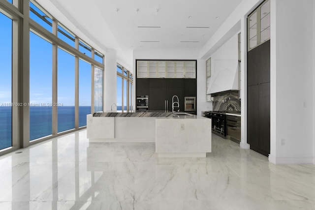 kitchen featuring oven, sink, a water view, floor to ceiling windows, and light tile patterned flooring