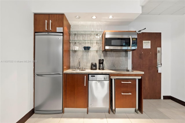 kitchen featuring appliances with stainless steel finishes, light tile patterned flooring, tasteful backsplash, and sink